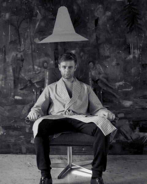 Austrian painter Philip Müller seated in an armchair in his Vienna studio in front of one of his large-scale paintings, black and white portrait